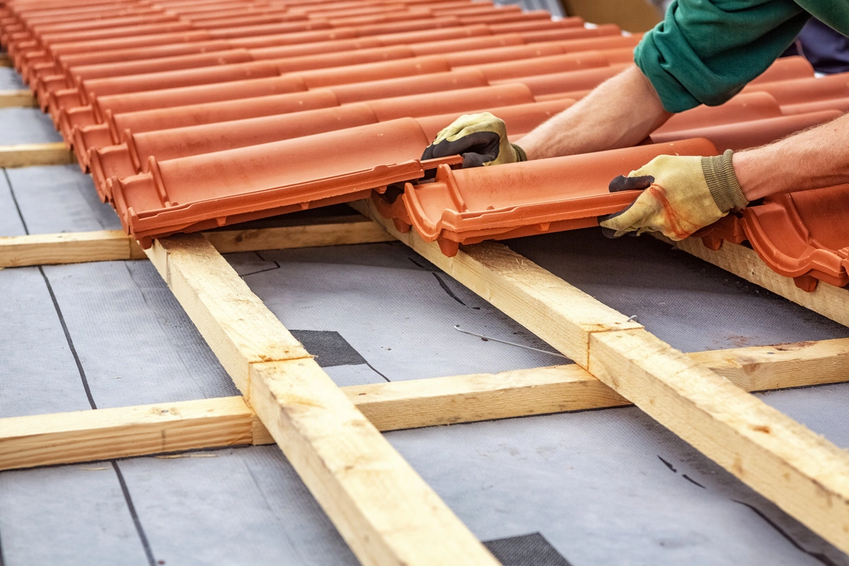 Installation de tuiles sur une charpente de toit.