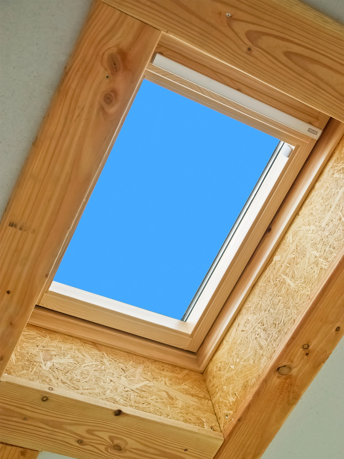 Fenêtre de toit Velux installée, vue intérieure avec ciel bleu.